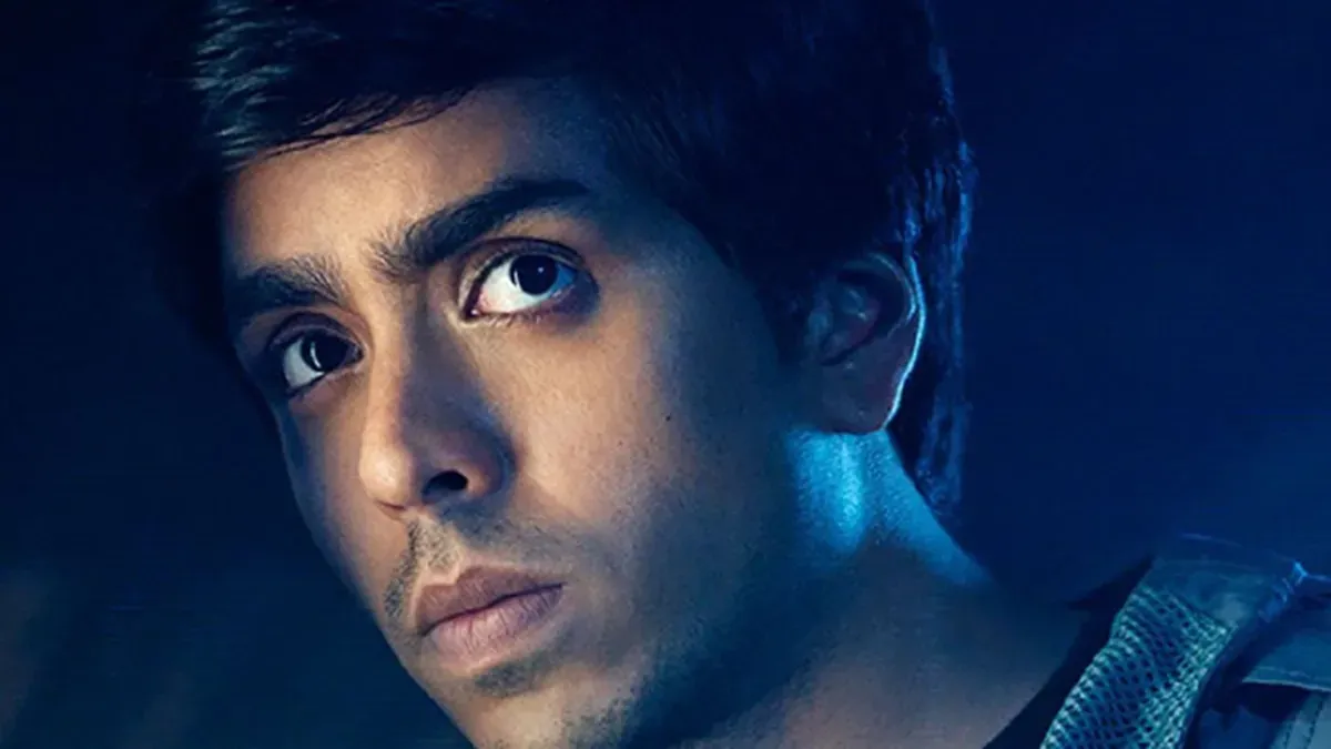 Adarsh Gourav and Peter Dinklage look intently into the distance in a dramatic sci-fi setting.