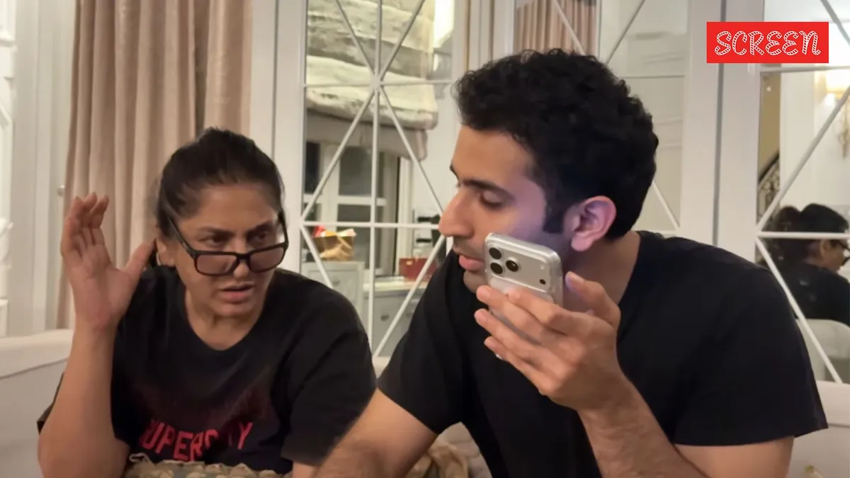 Archana Puran Singh smiling, with a hint of her son in the background.