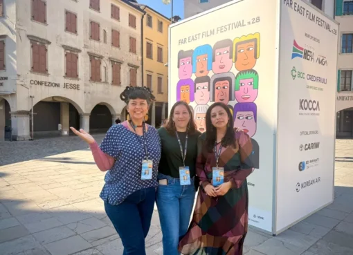 A group of diverse filmmakers discussing ideas at a film festival in Udine, Italy, with bright sunlight.