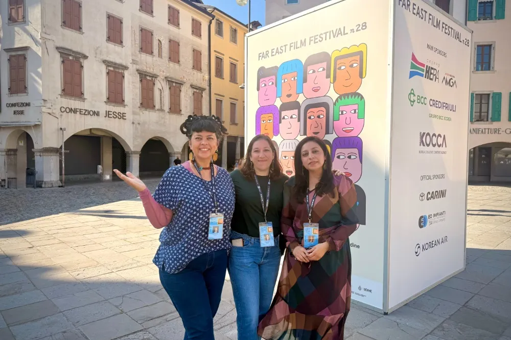 A group of diverse filmmakers discussing ideas at a film festival in Udine, Italy, with bright sunlight.
