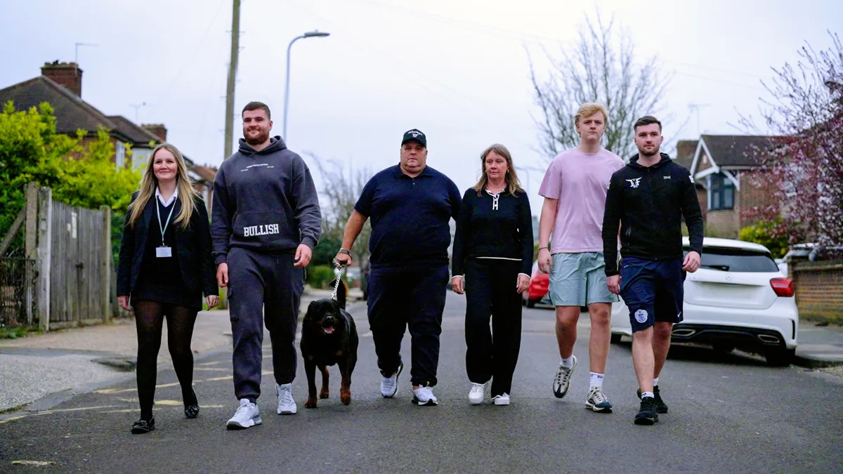 A family smiling, with a large spread of Chinese food.