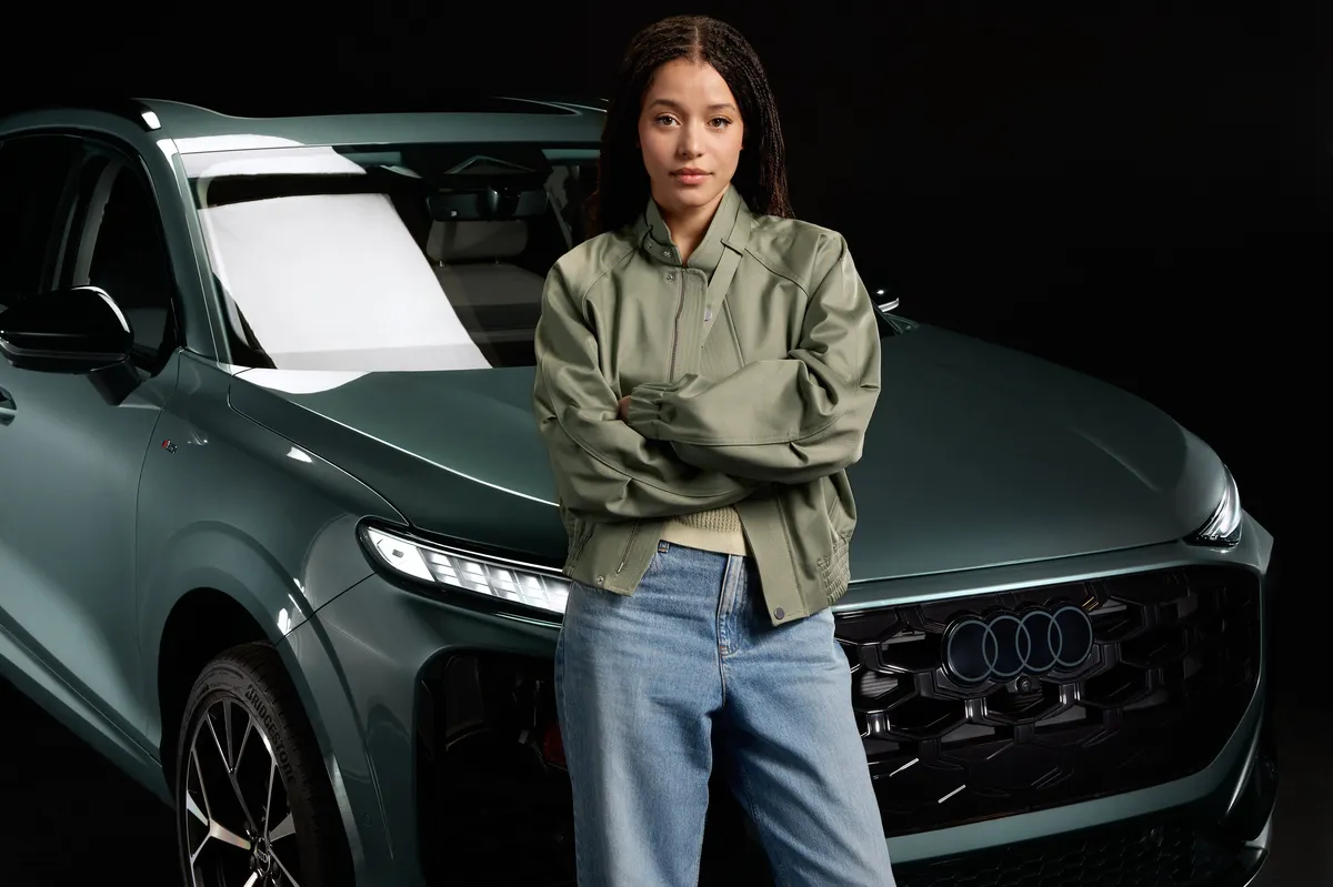 Chase Infiniti smiling, perhaps alongside a sleek Audi car.