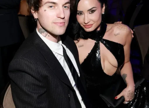 Demi Lovato and Jutes holding hands and singing together on a softly lit stage during a concert in New York City.