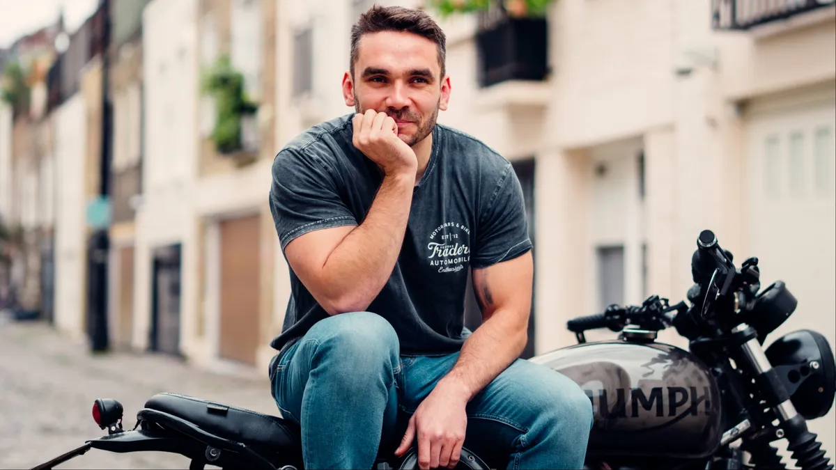 A man on a motorcycle, smiling.