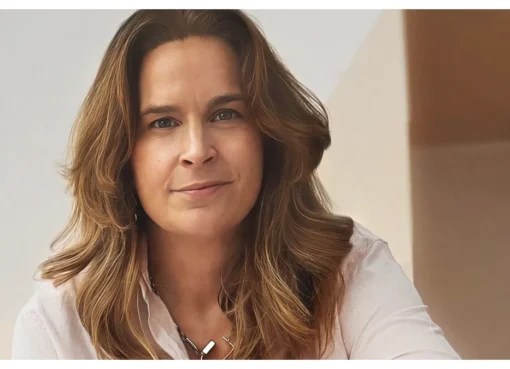 A professional woman, Sara May, smiling and looking confident in a business setting.