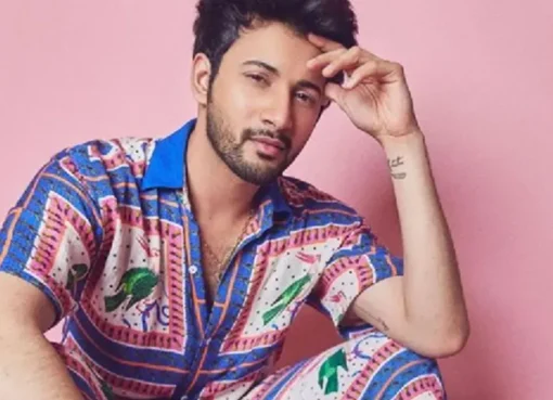A man wearing a vibrant floral shirt, with another man in a colorful Bandhani jacket in the background, showcasing new men's fashion trends.