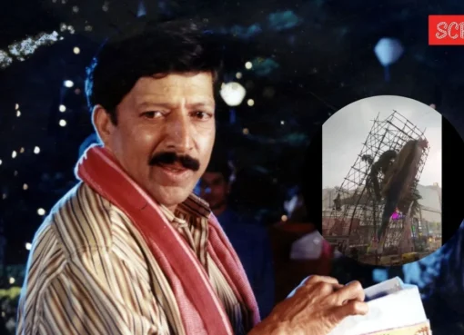 A collapsed, colorful giant cut-out of actor Vishnuvardhan lying across a busy road in Bengaluru, with debris scattered.