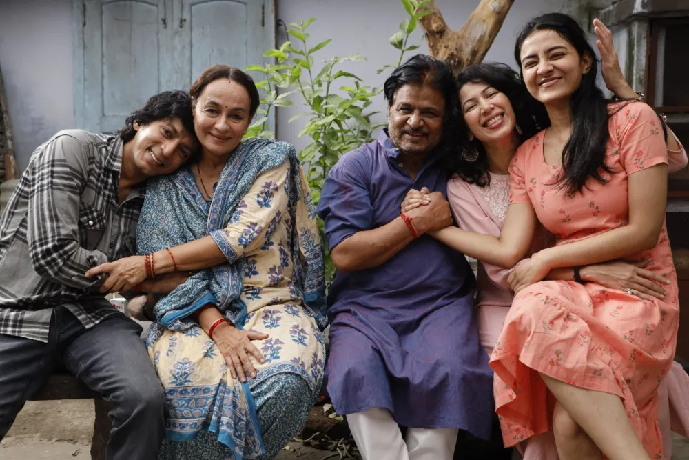 Actor-filmmaker Anshuman Jha smiling, possibly at a film festival, with a vibrant film reel graphic in the background.