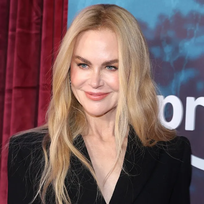Nicole Kidman standing tall and smiling in a stylish outfit.