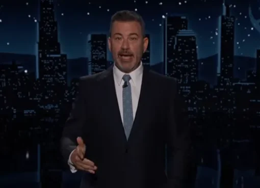 Jimmy Kimmel laughing on his late night show set with bright studio lights.