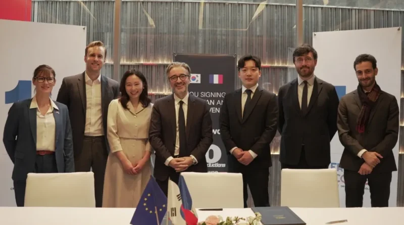 French and Korean executives shaking hands during a formal signing.