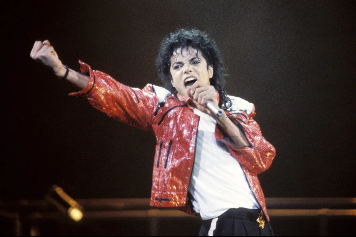 A dramatic close-up of Michael Jackson in his prime, with a fierce, focused expression.