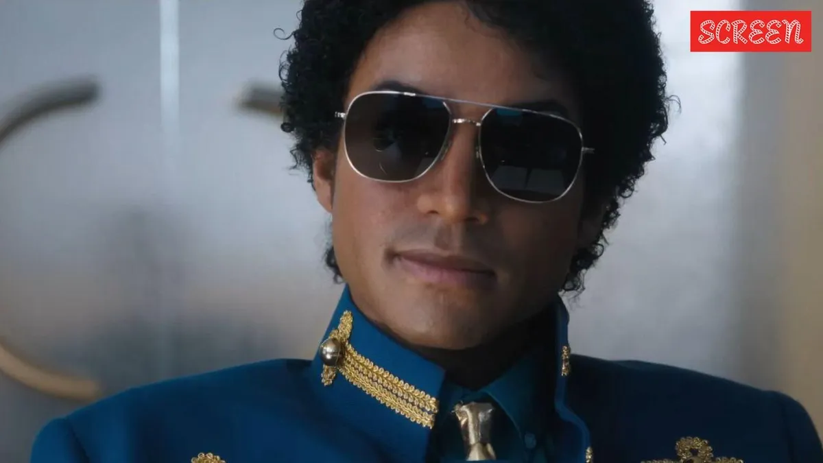 A performer on stage mimicking Michael Jackson's iconic dance pose in a gold jacket.