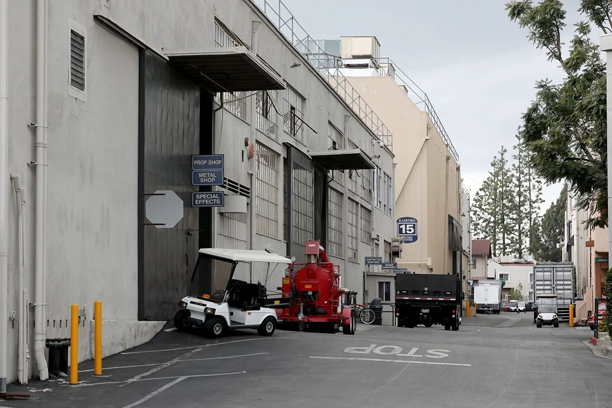 A view of studio buildings with a Hollywood sign in the distance.