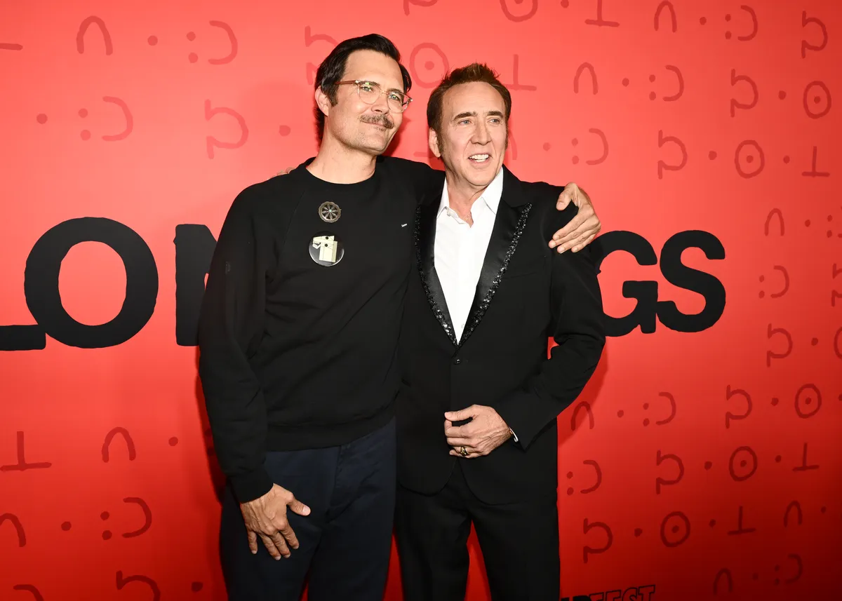 Nicolas Cage looking intensely, possibly from a horror movie still, with a dark and mysterious background.