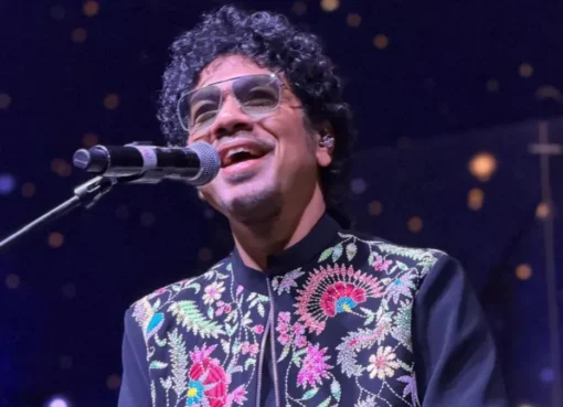 Papon singing passionately on stage under warm spotlights at a concert.