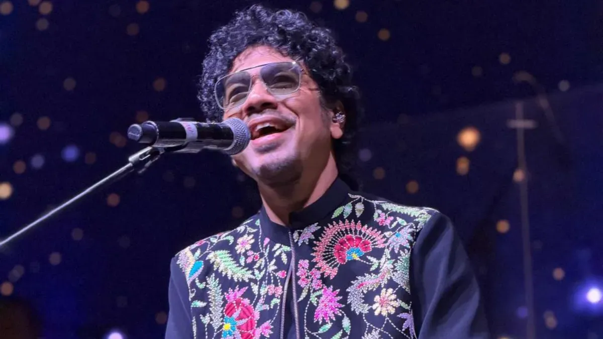 Papon singing passionately on stage under warm spotlights at a concert.