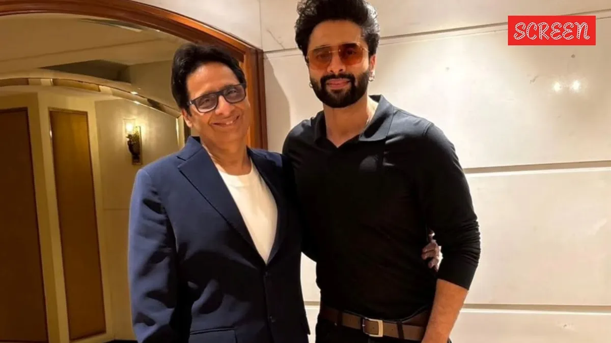 Vashu Bhagnani standing in a busy street market with sarees.