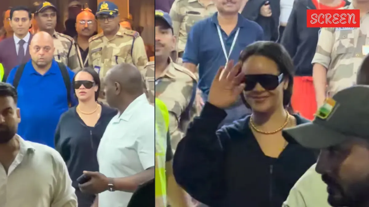 Rihanna smiling as paparazzi take photos.