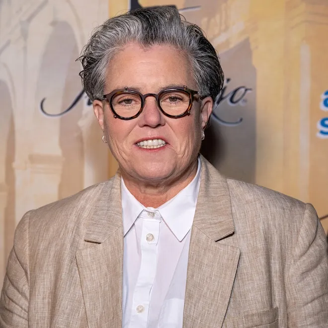 Rosie O'Donnell in a sparkly dress doing a dance move.