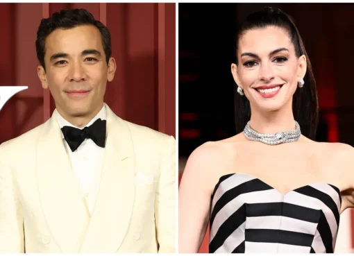 Anne Hathaway and Conrad Ricamora smiling and talking on a movie set, dressed in casual clothes.