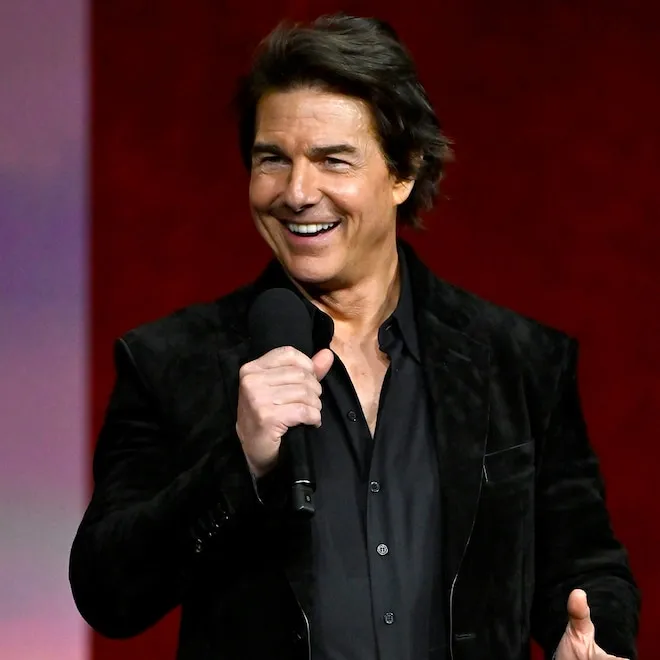 Tom Cruise in a flight suit with a determined expression.