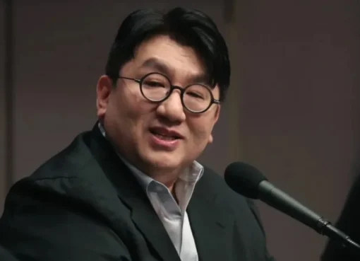 Bang Si-Hyuk standing in front of a modern background
