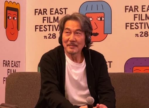 Koji Yakusho smiling, possibly on a film set.