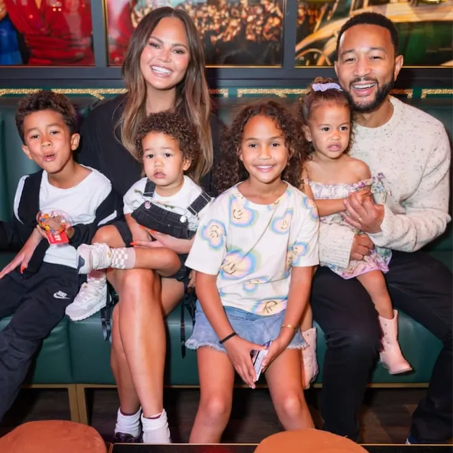 Chrissy Teigen and John Legend smiling happily with their four young children.