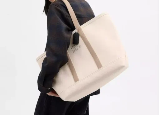 A stylish carry-on suitcase open with neatly packed travel accessories, next to a passport and sunglasses.