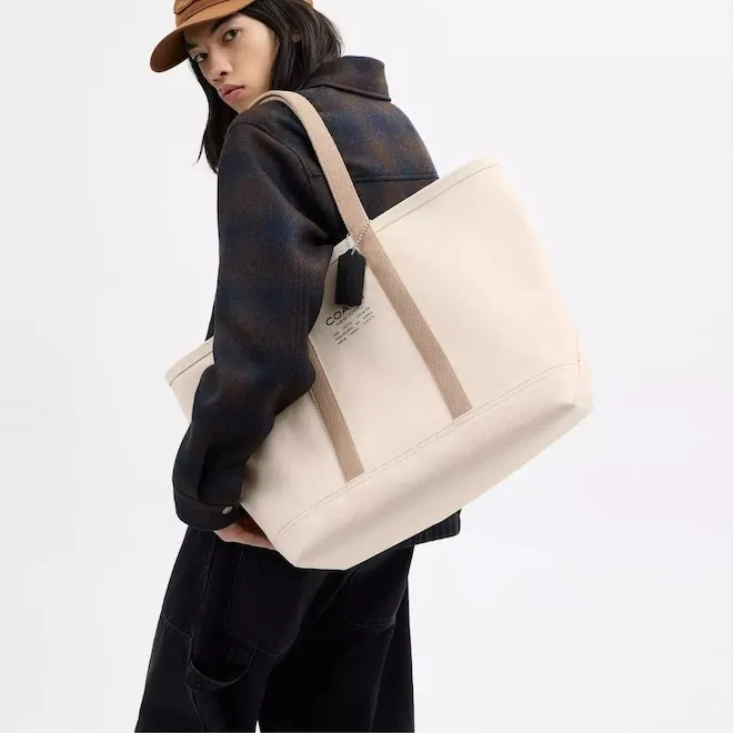 A stylish carry-on suitcase open with neatly packed travel accessories, next to a passport and sunglasses.