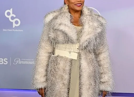 Queen Latifah on stage at the American Music Awards, holding a microphone, with a vibrant stage background.