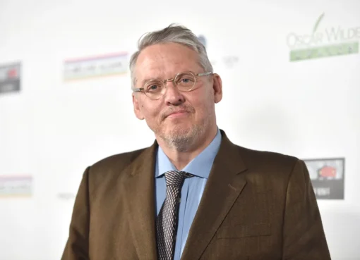 Adam McKay speaking passionately into a microphone during a podcast recording.