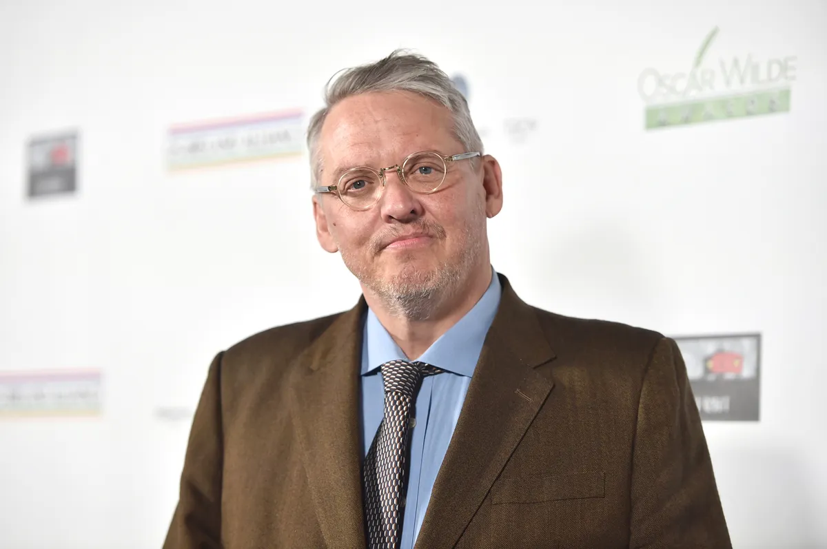 Adam McKay speaking passionately into a microphone during a podcast recording.