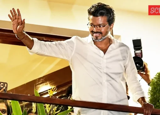 Vijay smiling and waving to a large crowd of fans from a balcony at his parents' home in Chennai.