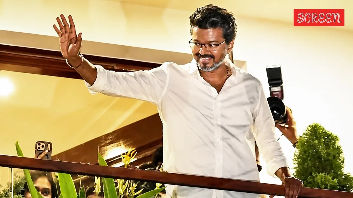 Vijay smiling and waving to a large crowd of fans from a balcony at his parents' home in Chennai.