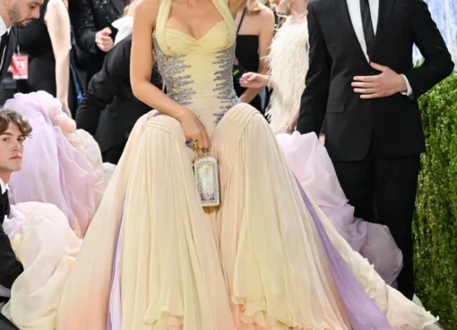 Blake Lively smiling and posing on the Met Gala red carpet in a beautiful multi-colored, layered pastel gown.