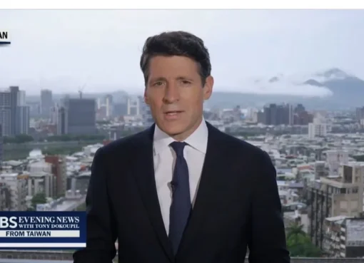 A slightly blurry, wide shot of a news anchor looking concerned during a live broadcast.