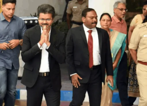 Tamil Nadu CM Vijay walking down a narrow airplane aisle while a flight attendant looks on in surprise.