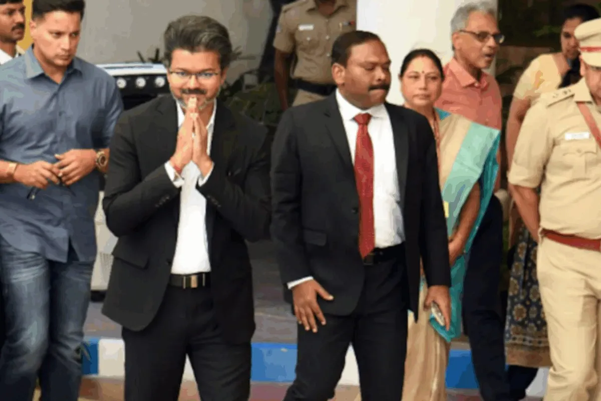Tamil Nadu CM Vijay walking down a narrow airplane aisle while a flight attendant looks on in surprise.