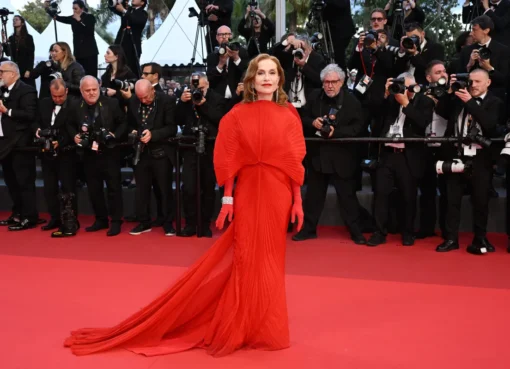 A celebrity walks the red carpet at the Cannes Film Festival, surrounded by photographers and fans.