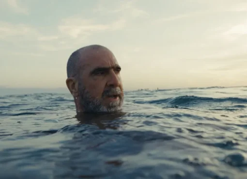 Close-up portrait of Eric Cantona with a serious, intense expression.