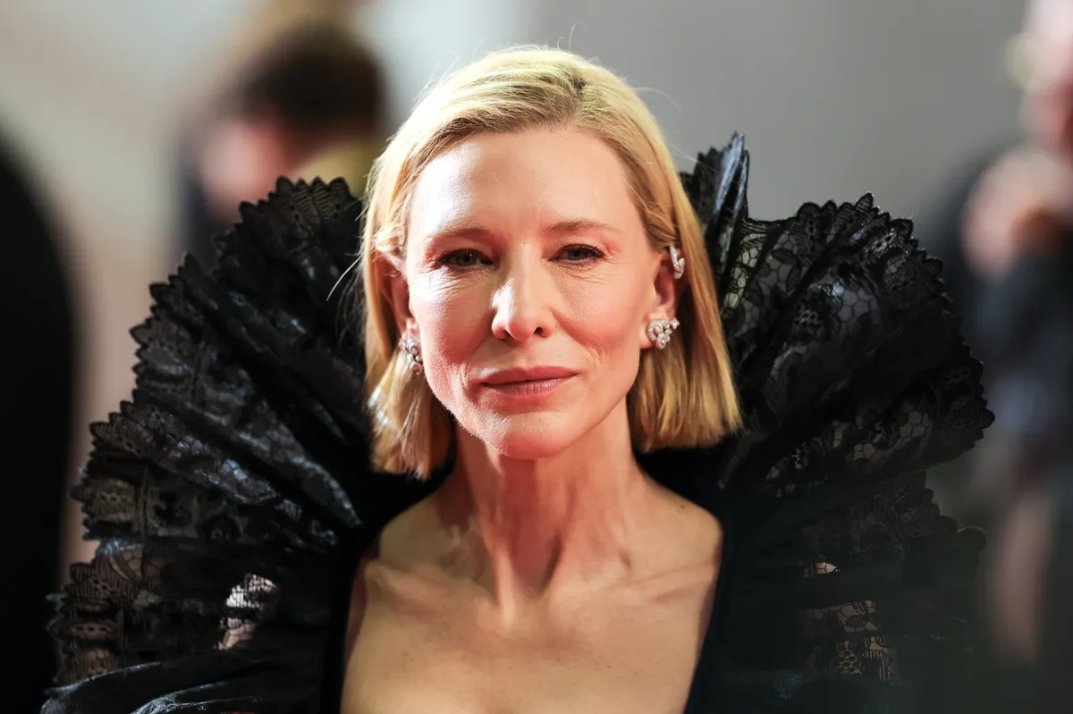 Cate Blanchett speaking thoughtfully at a film festival, looking serious.