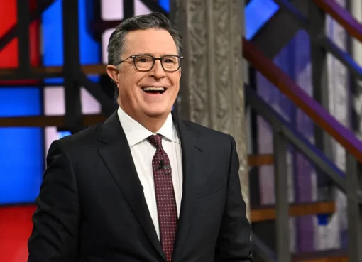 Stephen Colbert smiling at a party with a 'Fired and Festive' theme.