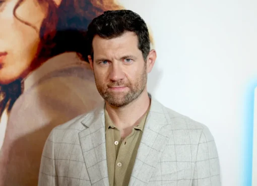 Billy Eichner smiling and holding a microphone, possibly in a street setting.