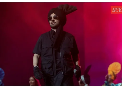 Diljit Dosanjh singing on stage with bright lights and a colorful turban.