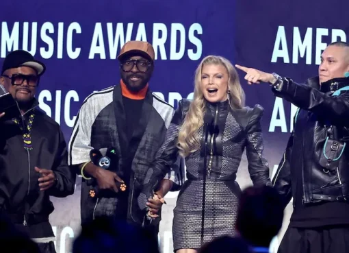 Fergie smiling on stage with will.i.am, Taboo, and apl.de.ap of the Black Eyed Peas.