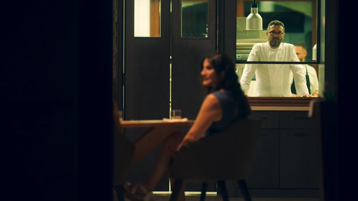 A close up of a chef carefully placing a garnish on a gourmet dish with tweezers