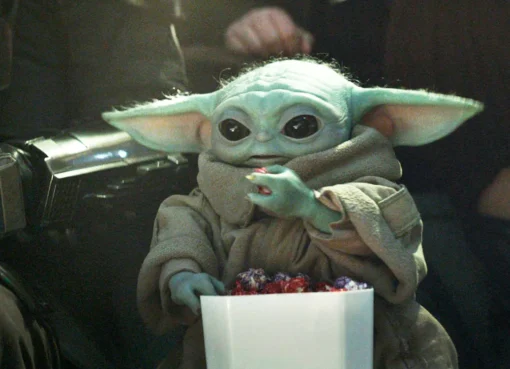 Close-up of Grogu, the cute green alien from Star Wars, looking curious.