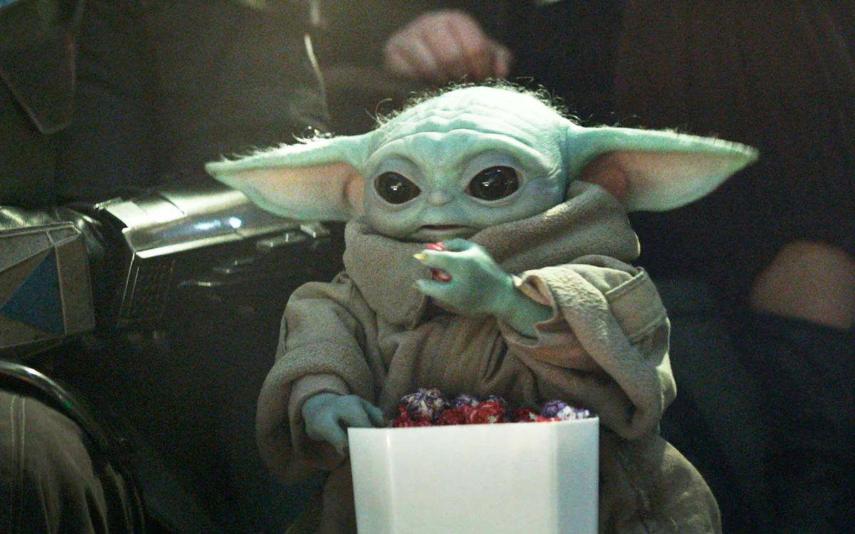 Close-up of Grogu, the cute green alien from Star Wars, looking curious.